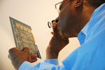 African American man with glasses inspecting a component